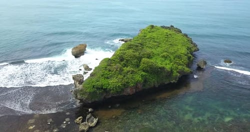Drone view of huge coral rock with clusters of small rocks that crushing by the wave on the tropical