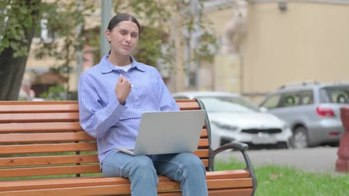 Woman Using Laptop, Massaging Wrist on Park Bench