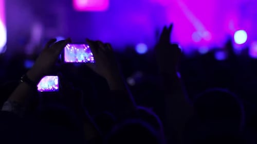 People at music rock concert taking photos or recording video with smartphones, party crowd cheering
