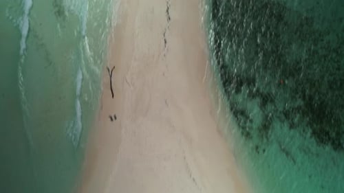A remote sandy beach with tents and turquoise water, aerial view