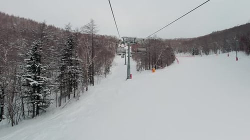 Riding on Ski Lift Above the Slopes Between Snow Covered Pinetrees POV Shot Winter Vacation Concept