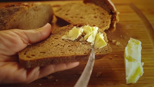 Close up of hand spreading butter with a knife on fresh toast