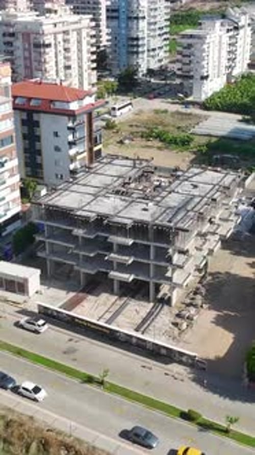 Vídeo vertical: trabajadores que operan en marcos y fachadas de metal con acabados de piedra capturados en un