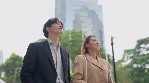 Asian young businessman and woman partner working outdoors in the city.