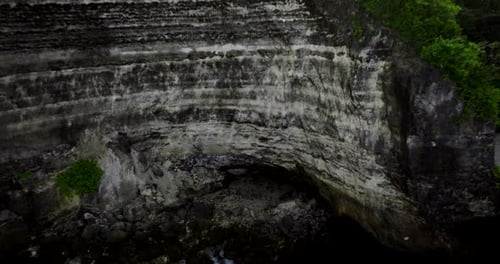 Rocky wall of high cliffs of Nusa Penida, Bali in Indonesia. Aerial backward ascending