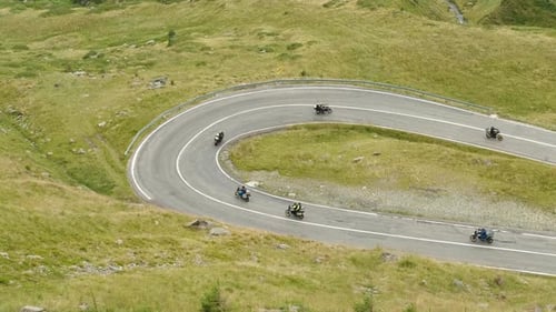 Grupo de ciclistas pedaleando por la sinuosa carretera de montaña