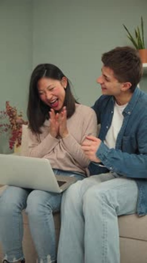 Happy Couple Using Laptop Computer on Couch Indoors