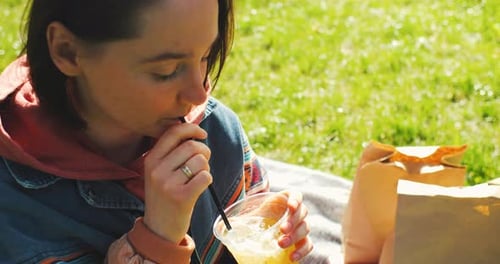 Beautiful Young Woman Drinks Cocktail in the Park Enjoys Spring Sunlight Spring Summer Lemonade