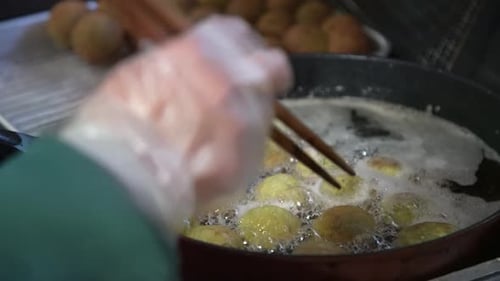 Gloved Hand Frying Green Falafel in Hot Oil