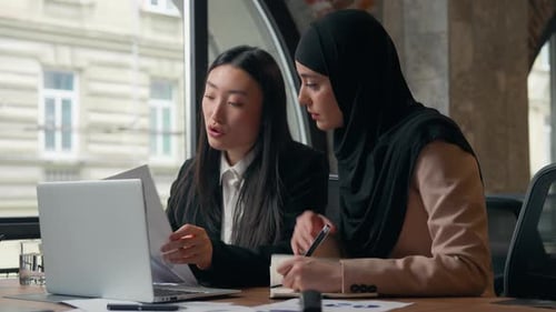 Two Women Working at a Table with Laptop