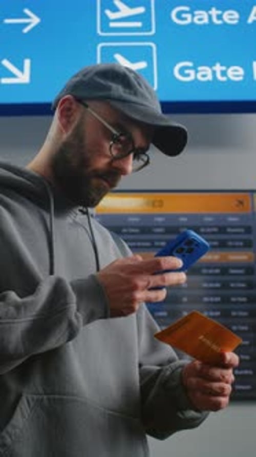 Man Checks Ticket and Phone in Airport