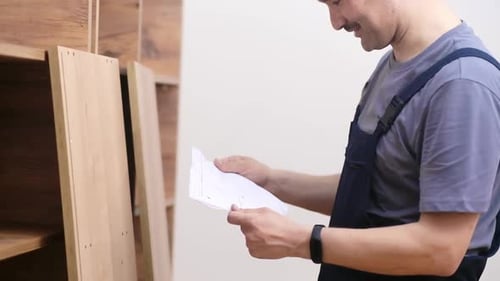 Man Reads Instructions For Wood Furniture Construction