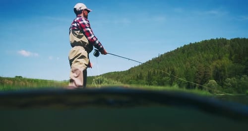 Fly fishing split underwater view. Angler stands in the river and casts the fly. Fisherman fishing o