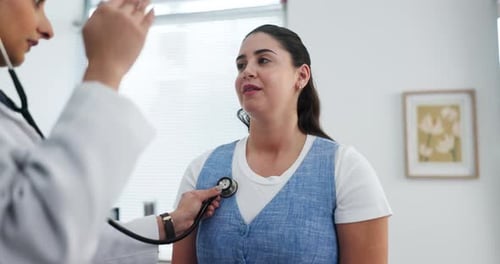 Doctor Listens to Woman with Stethoscope in Doctor's Office