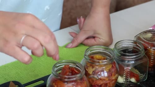 Woman Preserving Tomatoes Into Jars For Storage