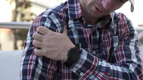Man Experiencing Shoulder Pain In A City Setting
