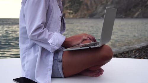 Geschäftsfrau mit digitaler Nomade arbeitet am Laptop am Meer