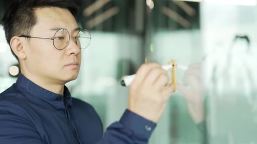 Empresário asiático ocupado, programador de TI com óculos, trabalha para escrever ideias em papel, adesivo, notas adesivas