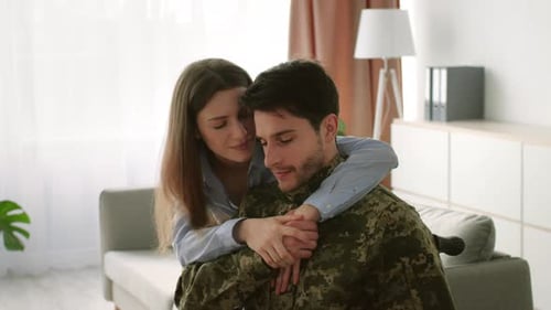 Loving Woman Hugs Soldier in Camouflage Shirt at Home