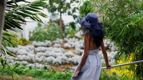 Woman Walks Through Tropical Garden in Summer Dress