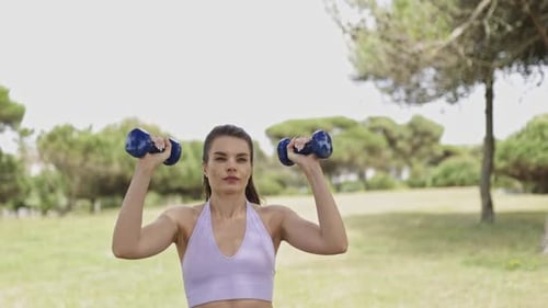 Woman Lifting Dumbbells in the Park for Fitness