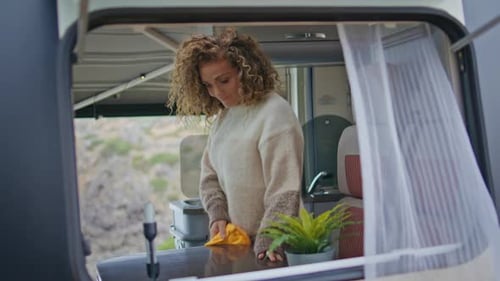 Woman Cleaning Counter in Tropical Camper Van