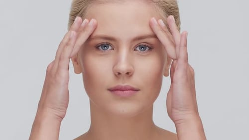 Studio Portrait of Young Beautiful and Natural Blond Woman Applying Skin Care Cream Face Lifting