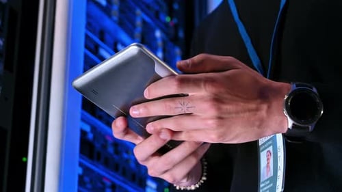 Nahaufnahme eines Mannes, der Daten auf einem Tablet in einem Serverraum analysiert