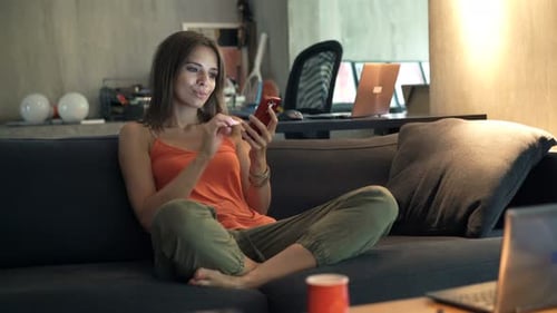Woman Relaxing on Couch Using Mobile Phone