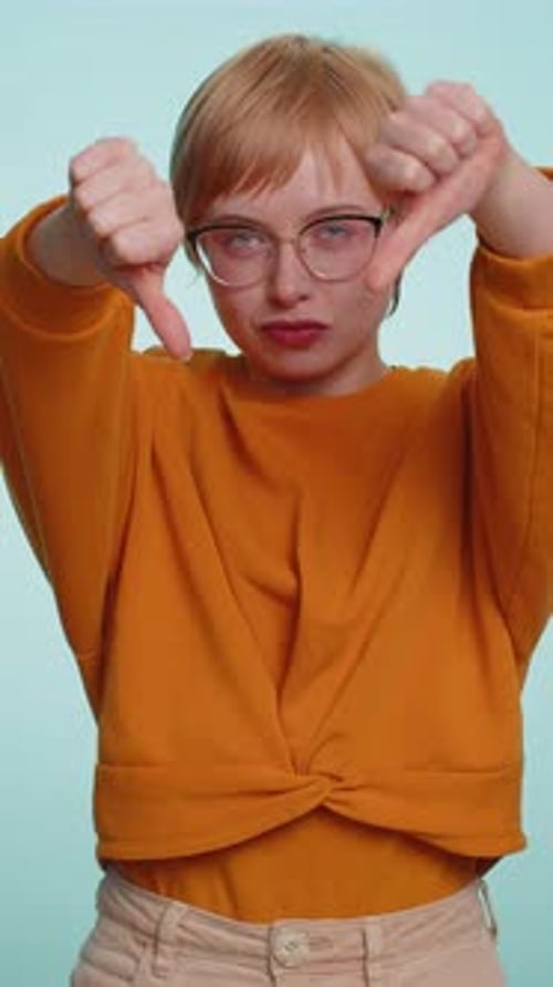 Displeased woman gives thumbs down gesture indoors