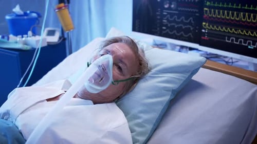 Senior woman in hospital bed with oxygen mask