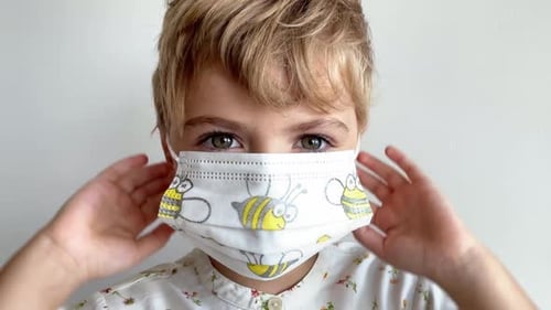 Close up child smiling face wearing face mask over white background. Children safety for flu protect
