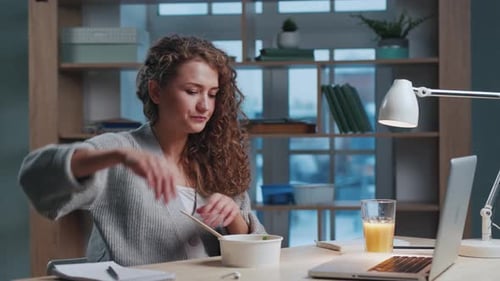 Woman at Lunch Eating Healthy Food and Watching Video on Laptop Computer at Home