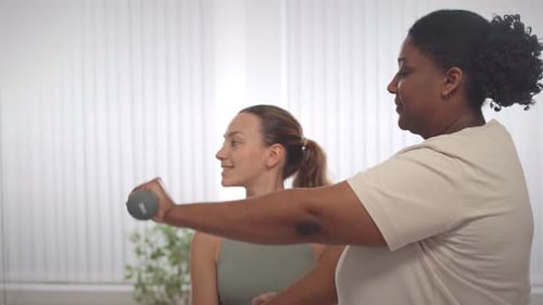 Woman with Trainer Doing Bicep Curls with Weights