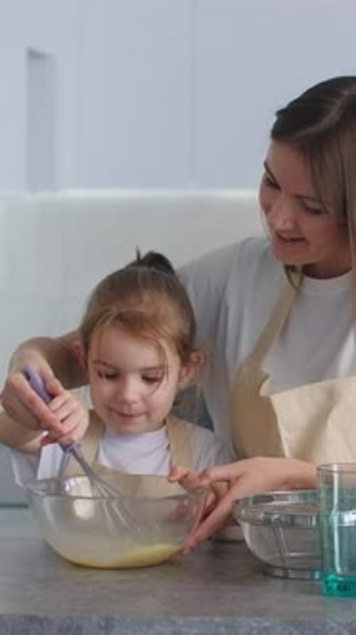 Girl Mixing Ingredients with Woman in Kitchen