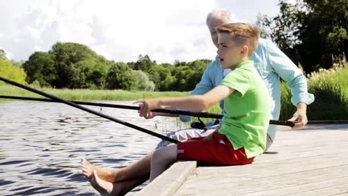 Happy grandfather and grandson enjoying summer fishing trip on the river