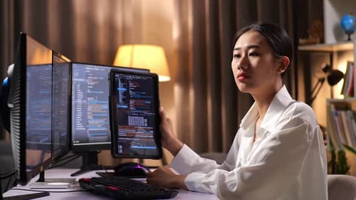 Asiatische Programmiererin schaut sich die Datenbank auf dem Tablet an, während sie eine App für die Entwicklung einer Software-Ingenieurin erstellt