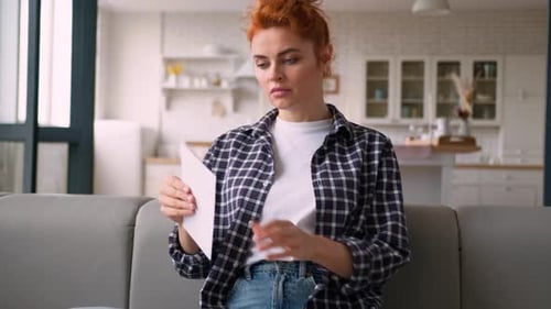 Woman Reading Letter Looks Surprised