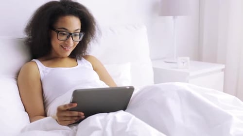 Woman Relaxing in Bed Using Tablet Device