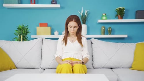 Woman Sitting on Sofa Experiences Stress and Anxiety