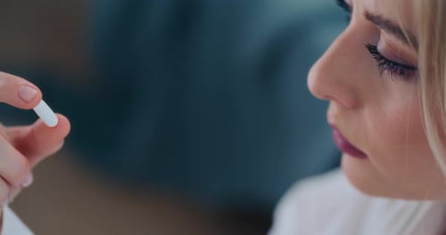 Woman Holding a White Pill Close Up Indoors