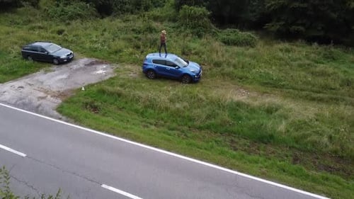 solo roadtrip man on blue SUV revealing green forest valley