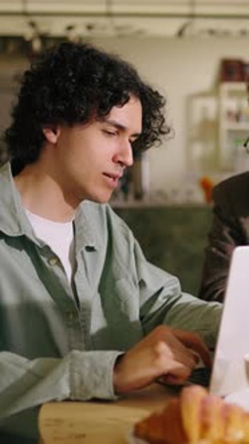 Jeunes adultes concentrés travaillant ensemble à une table de café décontractée avec des ordinateurs portables se concentrant sur un espace partagé
