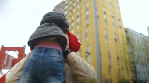 Ralenti, une maman heureuse tient son petit fils dans ses bras tendus et virevolte avec lui tout en
