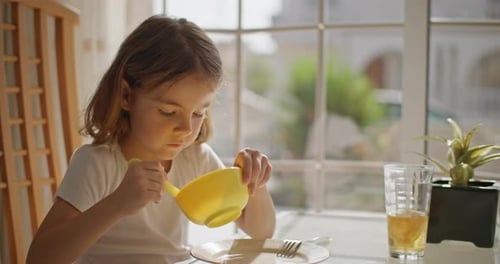 Young Girl Eating Breakfast at Sunny Table