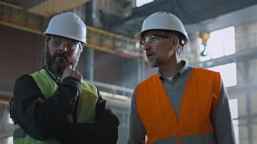 Two Heavy Industry Technicians Have Discussion About Production Process in Factory