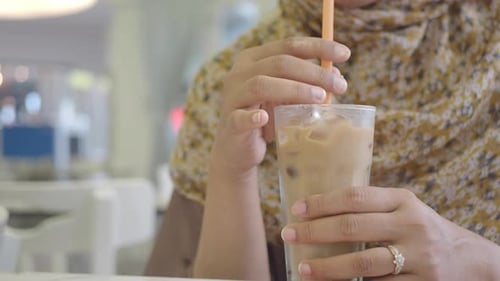 Enjoying a Refreshing Iced Beverage in a Cozy Cafe Setting