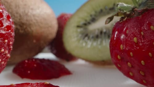 Red-green jelly with pieces of kiwi and strawberries inside. I eat green jelly with a spoon.