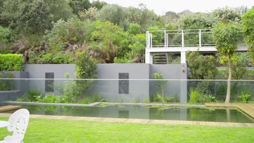 Camera is starting to pan to reveal pool, deck, table, shrubs and tree for garden tour