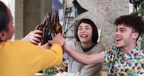 Friends Toasting with Beer Bottles at Indoor Gathering